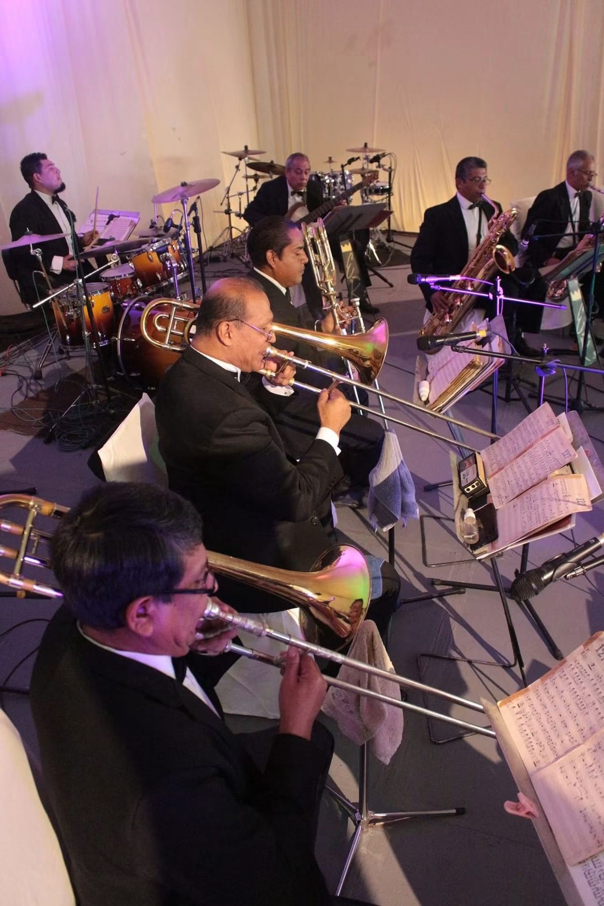 Sección de metales de la orquesta tocando trombones y saxofones durante un evento